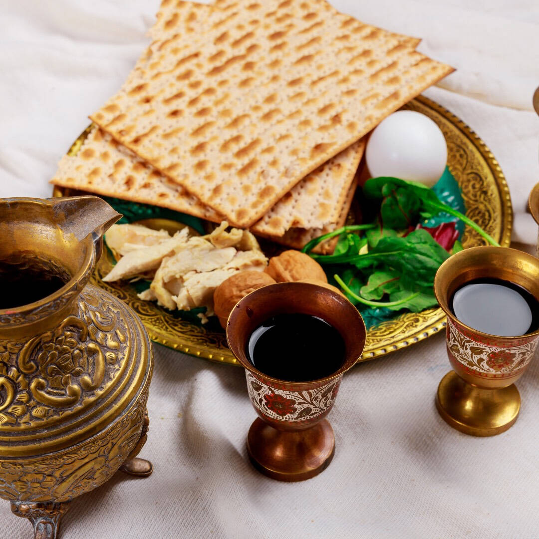 A seder plate with matzah and other traditional items alongside two cups of wine.